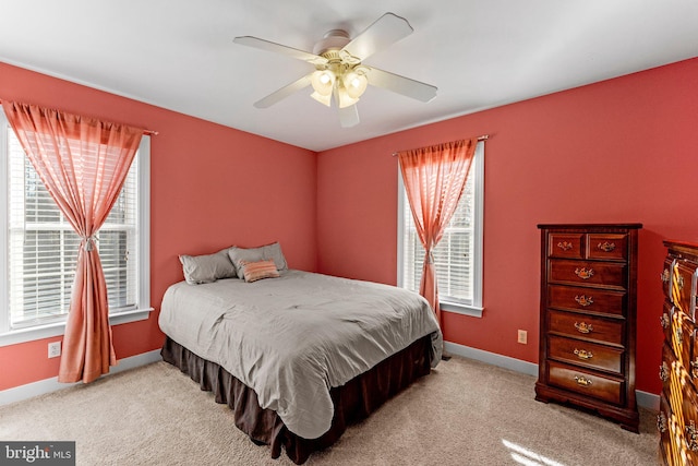 carpeted bedroom featuring multiple windows and ceiling fan