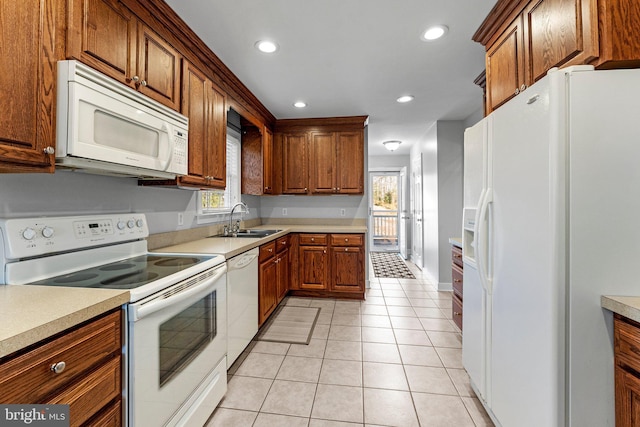 kitchen featuring light tile patterned flooring, white appliances, and sink