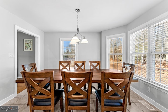 dining area with light tile patterned floors, a wealth of natural light, and an inviting chandelier