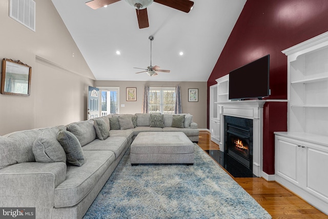 living room with ceiling fan, high vaulted ceiling, and wood-type flooring