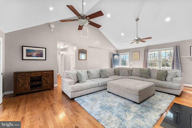 living room with ceiling fan, light hardwood / wood-style floors, and high vaulted ceiling