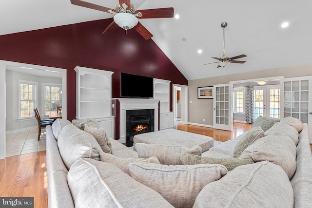 living room featuring french doors, light hardwood / wood-style floors, high vaulted ceiling, and a healthy amount of sunlight