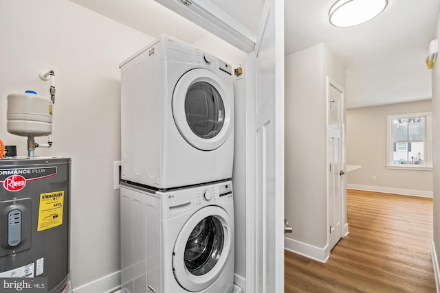 laundry room featuring hardwood / wood-style flooring, stacked washer / drying machine, and water heater