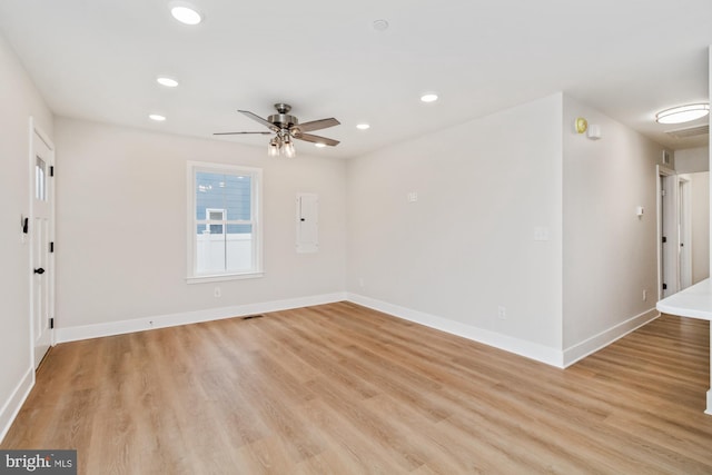 unfurnished room featuring electric panel, light hardwood / wood-style flooring, and ceiling fan