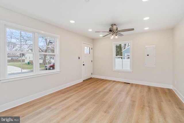 interior space with ceiling fan, electric panel, light hardwood / wood-style floors, and a wealth of natural light