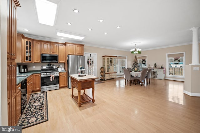 kitchen featuring stainless steel appliances, crown molding, a notable chandelier, a center island, and light hardwood / wood-style floors