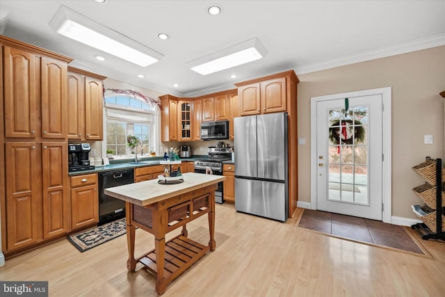 kitchen featuring light wood-type flooring, stainless steel appliances, and ornamental molding