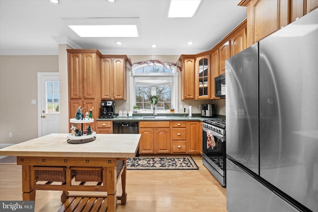 kitchen featuring a healthy amount of sunlight, light wood-type flooring, ornamental molding, and black appliances