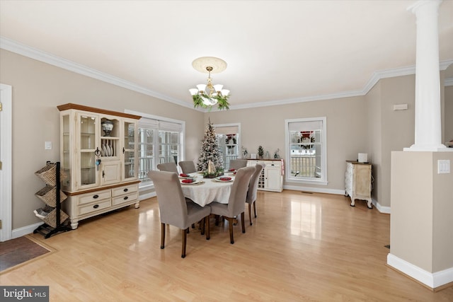 dining room featuring light hardwood / wood-style floors, ornate columns, crown molding, and an inviting chandelier