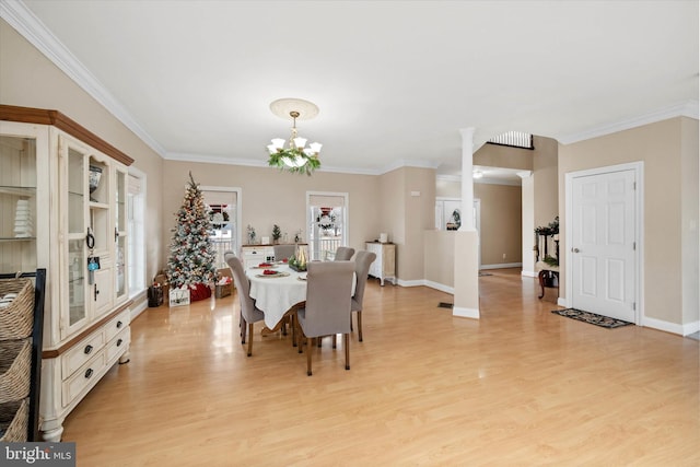 dining area featuring light wood-type flooring, decorative columns, an inviting chandelier, and crown molding