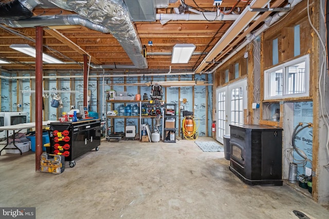 interior space featuring french doors, concrete flooring, a workshop area, washer / dryer, and a wood stove