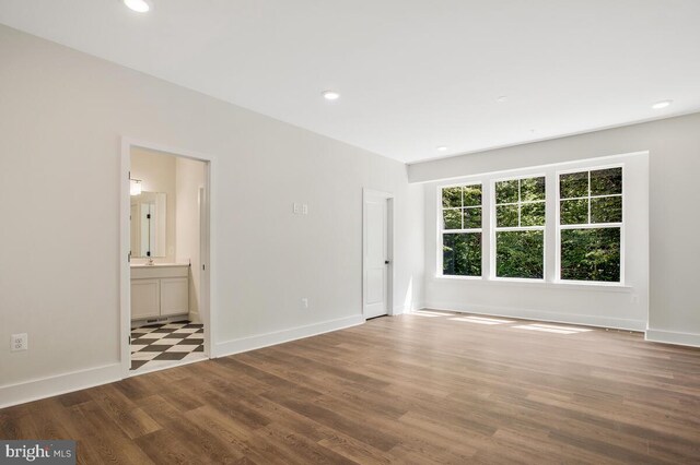 empty room with baseboards, wood finished floors, and recessed lighting