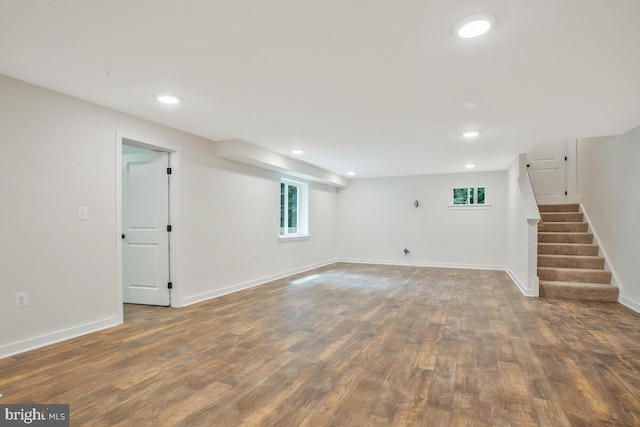 basement with stairway, recessed lighting, wood finished floors, and baseboards