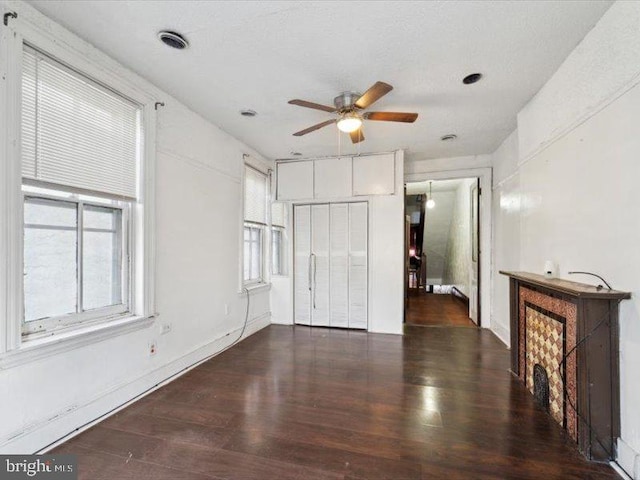 unfurnished living room featuring ceiling fan and dark wood-type flooring