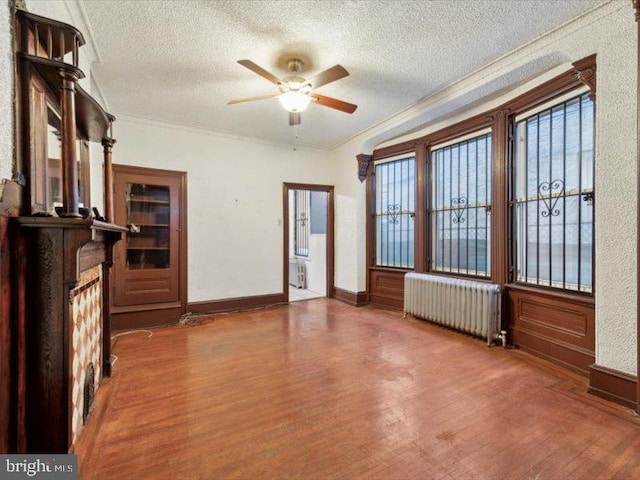 unfurnished living room with radiator heating unit, a textured ceiling, dark hardwood / wood-style floors, and ornamental molding