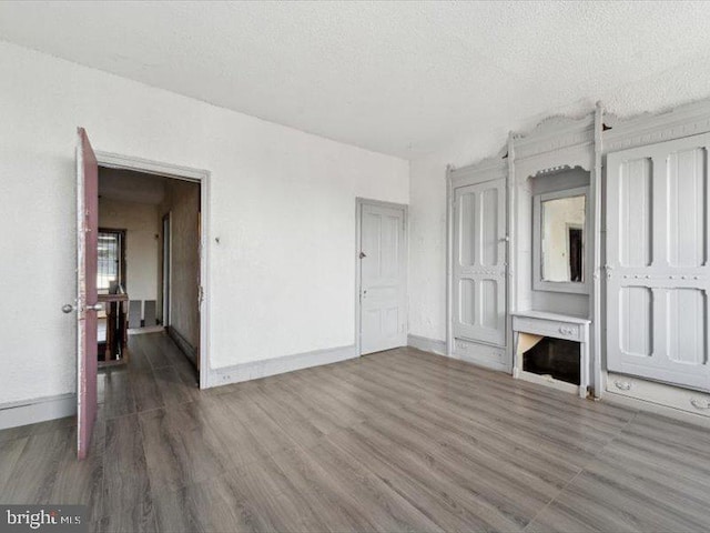 unfurnished living room with dark wood-type flooring and a textured ceiling