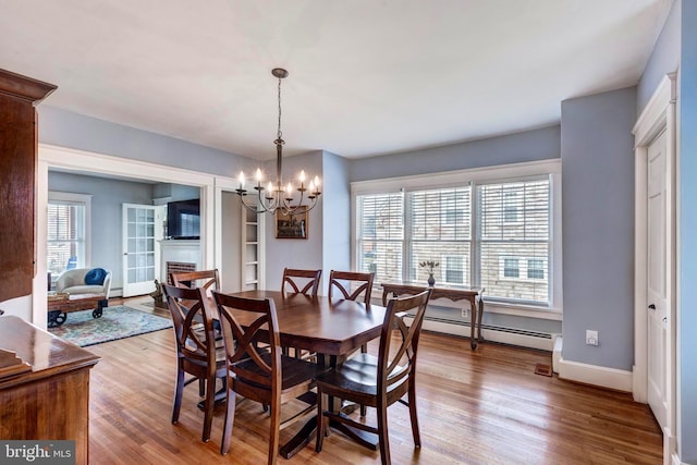 dining space featuring a baseboard radiator, an inviting chandelier, and light hardwood / wood-style flooring