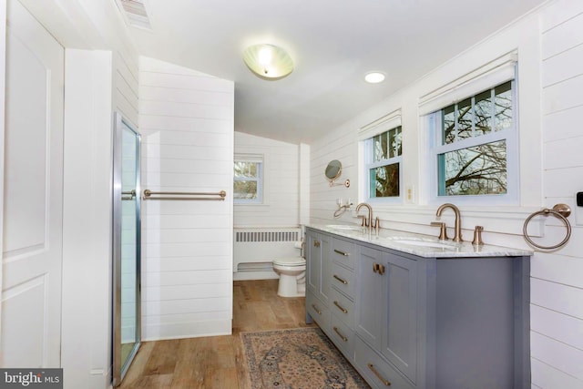 bathroom with toilet, a wealth of natural light, hardwood / wood-style floors, and radiator heating unit