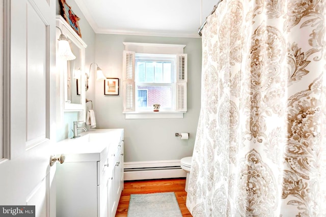 bathroom featuring vanity, baseboard heating, crown molding, hardwood / wood-style flooring, and toilet