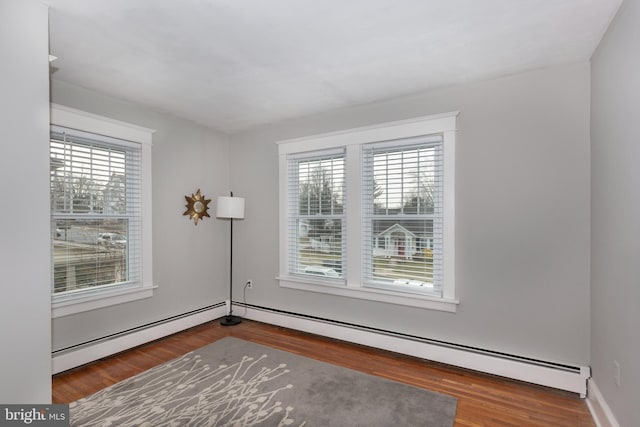 unfurnished room with hardwood / wood-style flooring, a wealth of natural light, and a baseboard heating unit