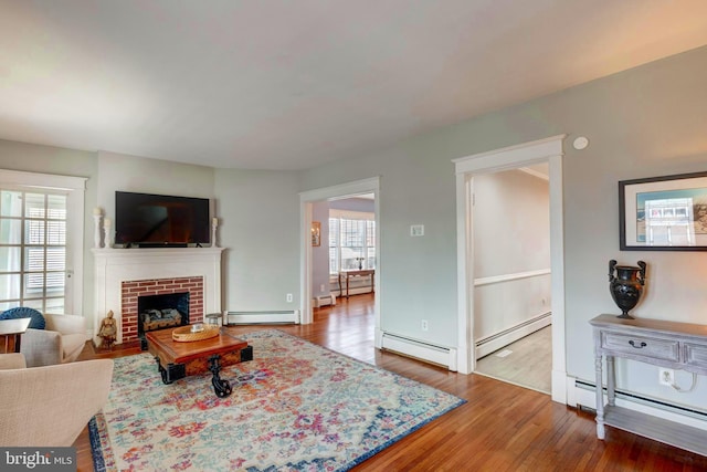 living room featuring baseboard heating, a fireplace, and wood-type flooring