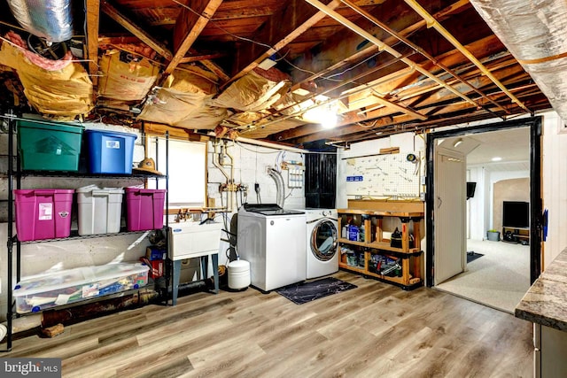 basement featuring washer and dryer, light hardwood / wood-style flooring, and sink