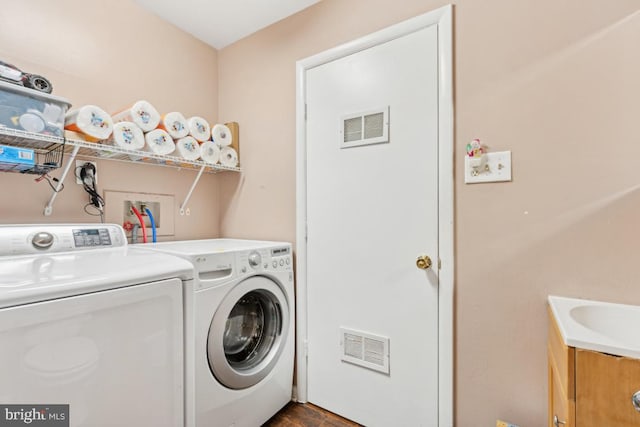 clothes washing area with sink, dark hardwood / wood-style flooring, and washing machine and clothes dryer