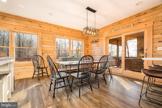 dining space featuring wooden walls and dark hardwood / wood-style flooring