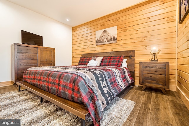 bedroom with dark hardwood / wood-style floors and wood walls