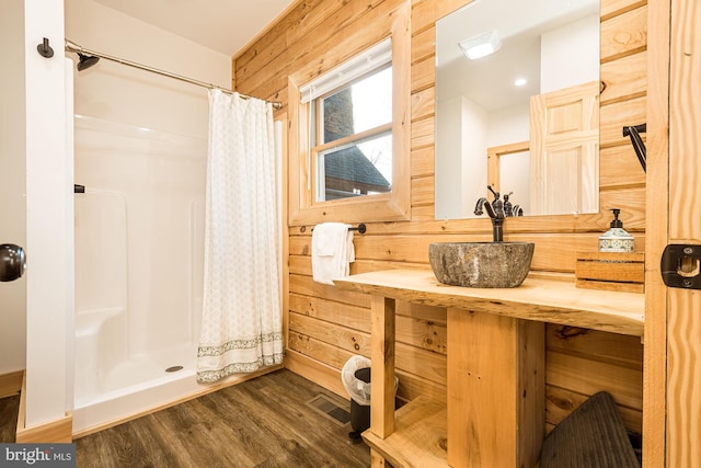 bathroom featuring hardwood / wood-style flooring, vanity, curtained shower, and wood walls