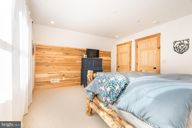 carpeted bedroom featuring lofted ceiling and wooden walls