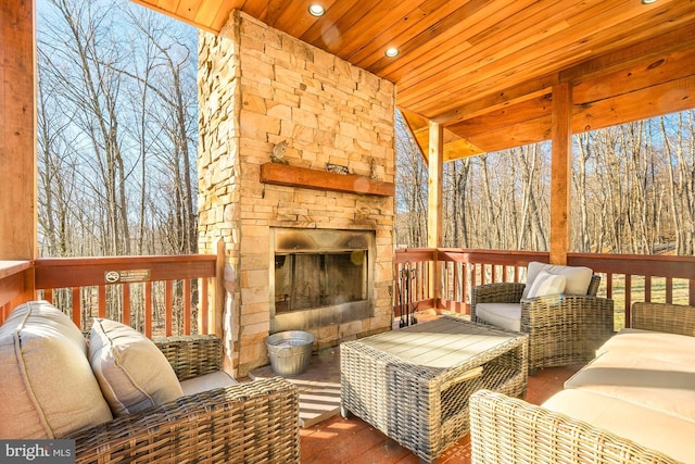 wooden terrace featuring an outdoor stone fireplace