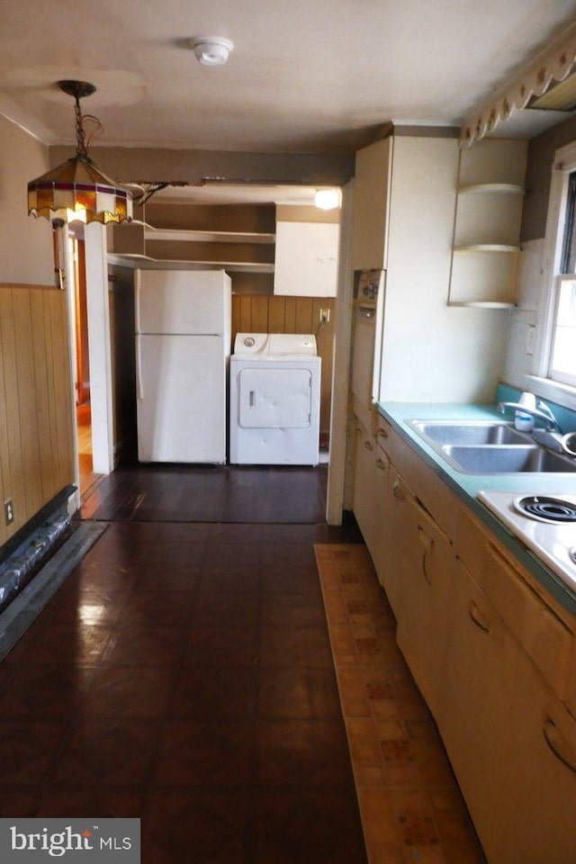 kitchen featuring sink, white refrigerator, washer / clothes dryer, decorative light fixtures, and wooden walls