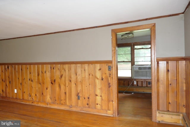 unfurnished room featuring wooden walls, hardwood / wood-style floors, cooling unit, and ornamental molding