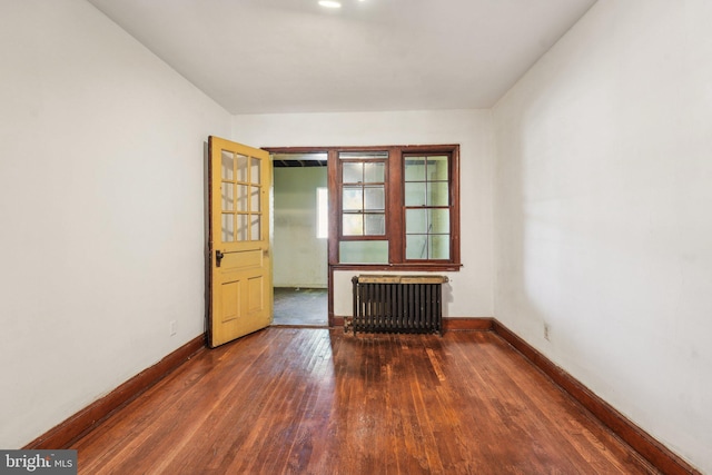 unfurnished room featuring radiator heating unit and dark wood-type flooring