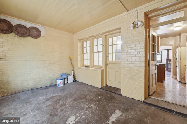 doorway to outside featuring a wealth of natural light and brick wall