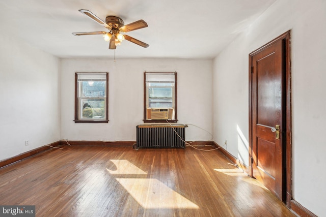 unfurnished room featuring ceiling fan, radiator heating unit, cooling unit, and wood-type flooring