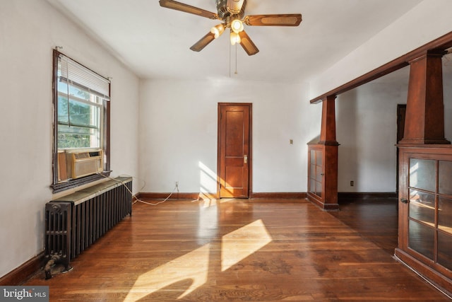 living room featuring cooling unit, dark hardwood / wood-style floors, ceiling fan, radiator heating unit, and decorative columns