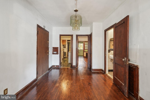 hall with dark wood-type flooring and a notable chandelier