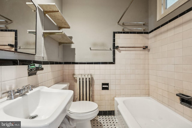 bathroom featuring a bath, tile walls, radiator, and sink