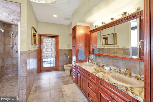 bathroom with toilet, a wealth of natural light, tile walls, and vanity