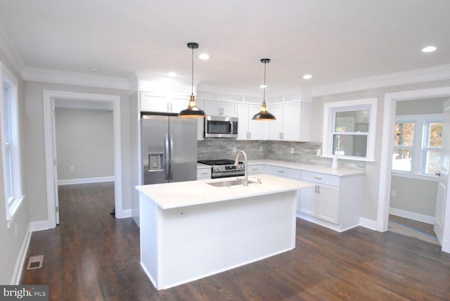 kitchen with a center island with sink, white cabinets, hanging light fixtures, sink, and appliances with stainless steel finishes