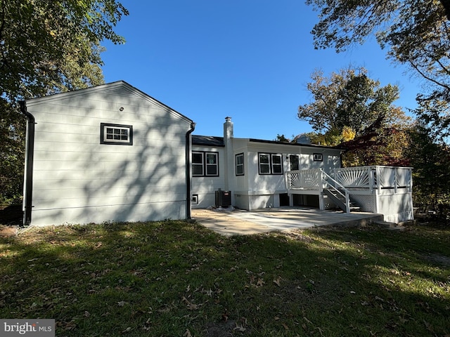 rear view of house featuring a lawn, a wooden deck, a patio, and central air condition unit