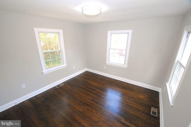 empty room featuring dark hardwood / wood-style flooring and a wealth of natural light