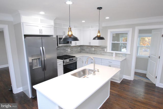 kitchen featuring dark wood-type flooring, a center island with sink, sink, appliances with stainless steel finishes, and decorative light fixtures