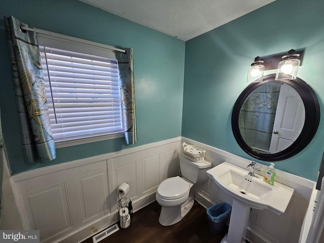 bathroom with hardwood / wood-style floors, toilet, and a textured ceiling