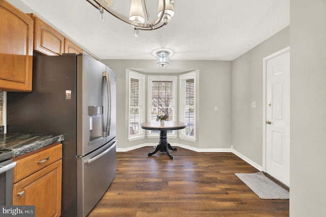 kitchen featuring dark stone countertops, stainless steel fridge with ice dispenser, dark hardwood / wood-style flooring, and a notable chandelier