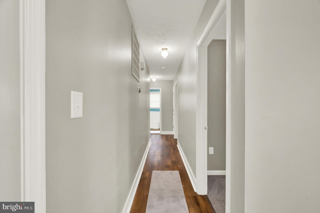 corridor with dark wood-type flooring and a textured ceiling