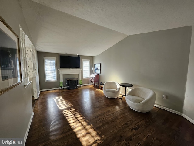 sitting room with a textured ceiling, dark wood-type flooring, and vaulted ceiling