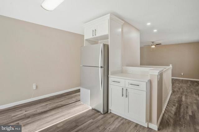 kitchen with white cabinetry, white fridge, and wood-type flooring